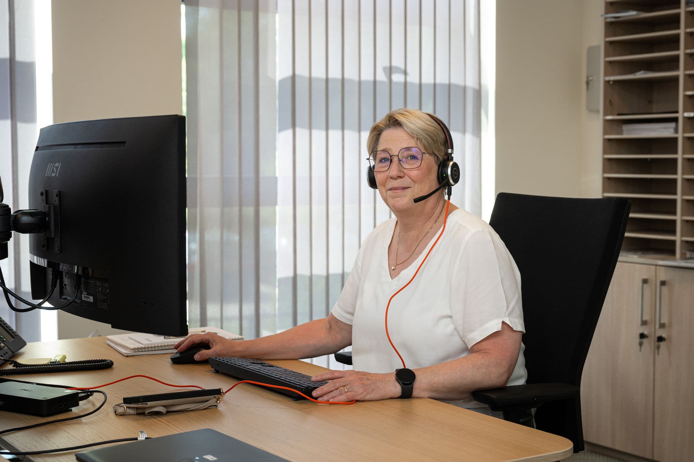 Collega van Accombis met headset aan haar bureau