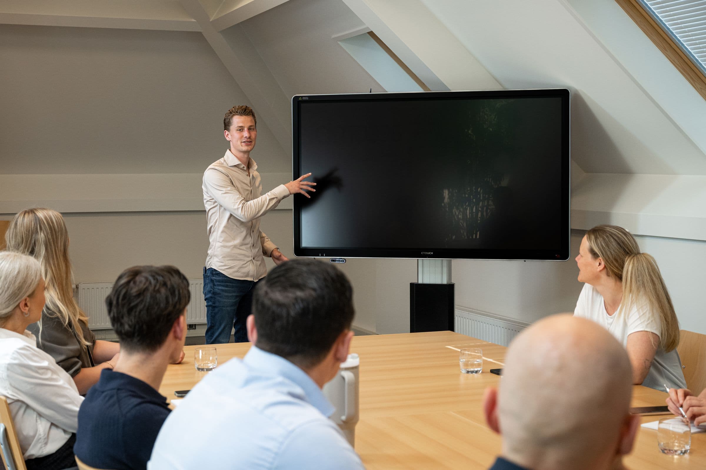 Collega van Accombis licht iets toe op het scherm terwijl het team meekijkt