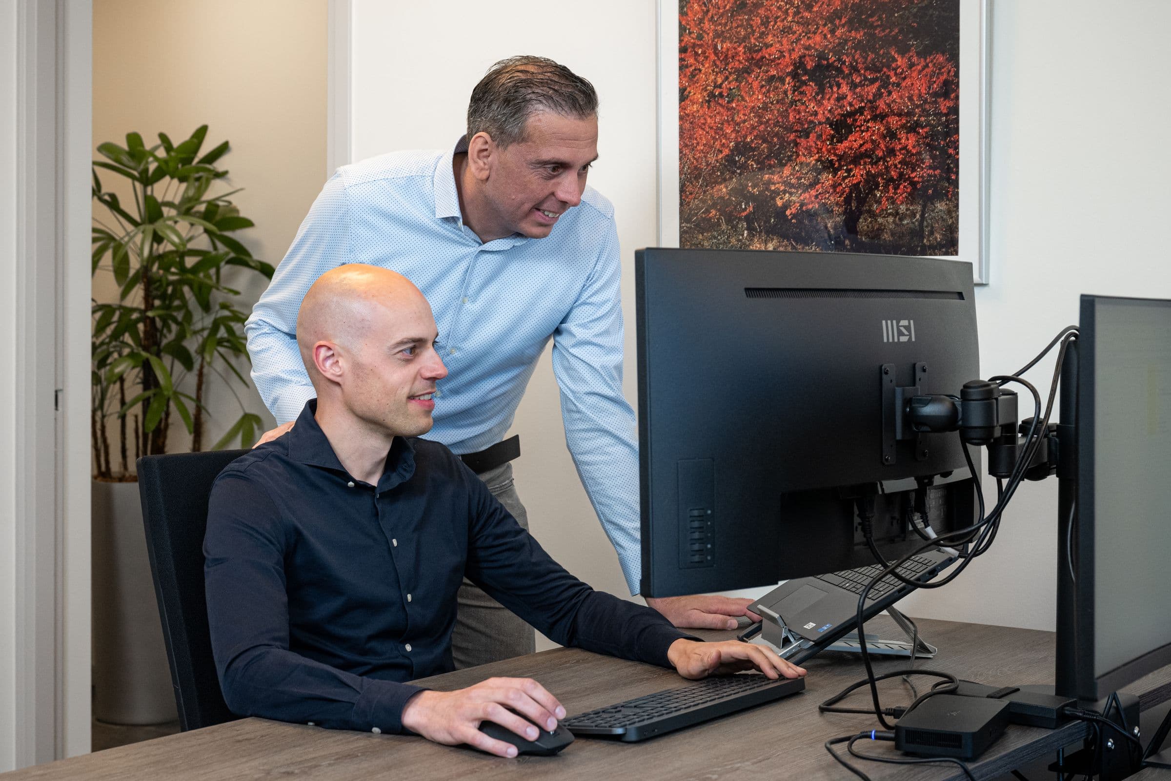 Twee collega's van Accombis overleggen aan hun schermen