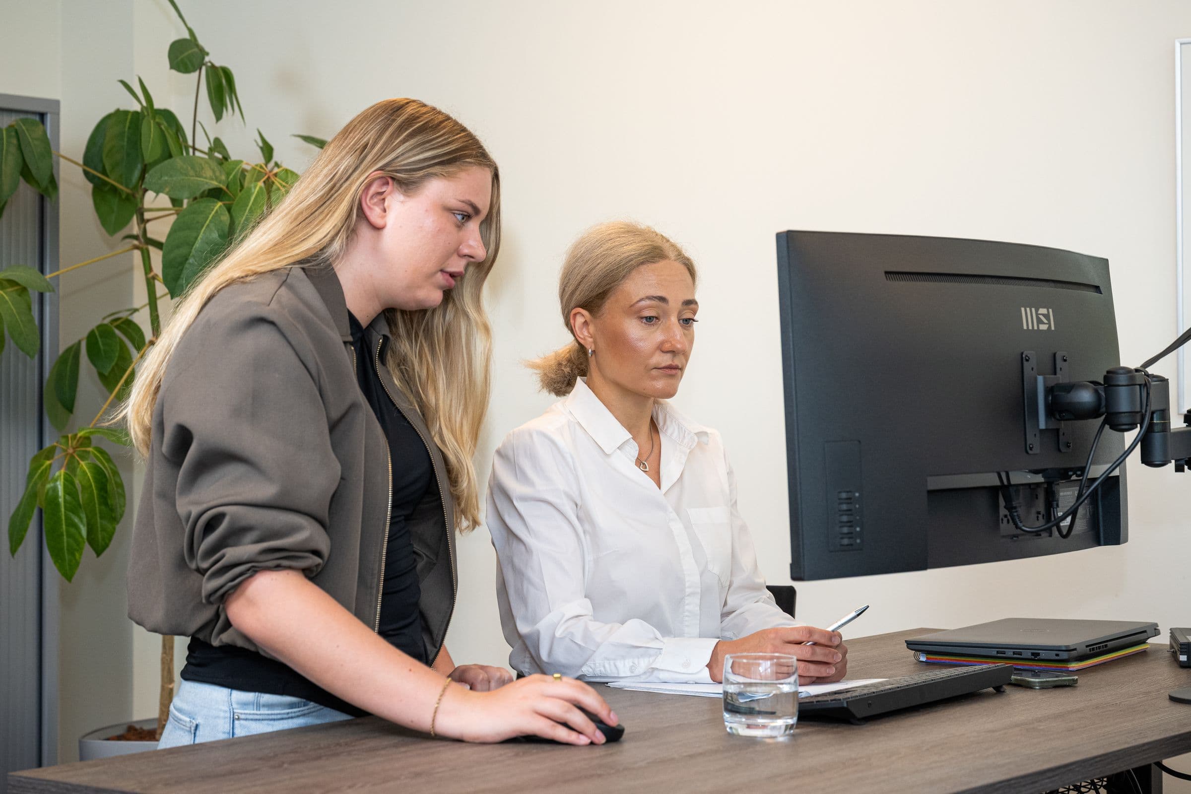 Twee collega's van Accombis overleggen samen aan een bureau
