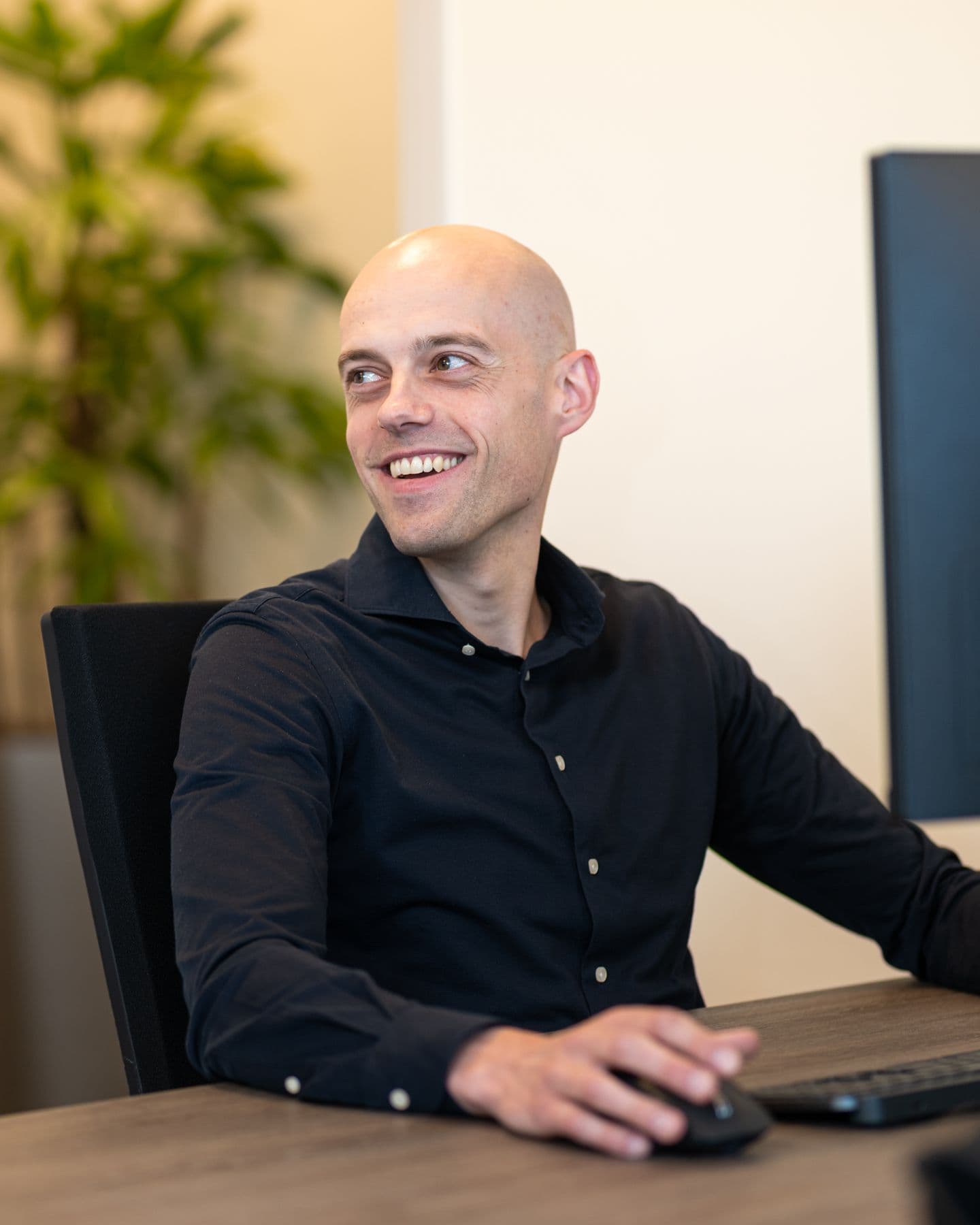 Collega van Accombis lacht breed aan zijn bureau
